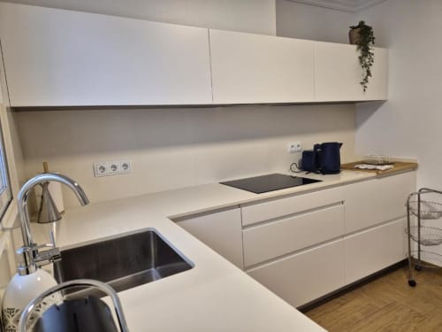 Cocina moderna blanca con fregadero de acero inoxidable, placa de cocción y amplio espacio de trabajo en Aloha Calpe Old Town Apartment, Calpe
