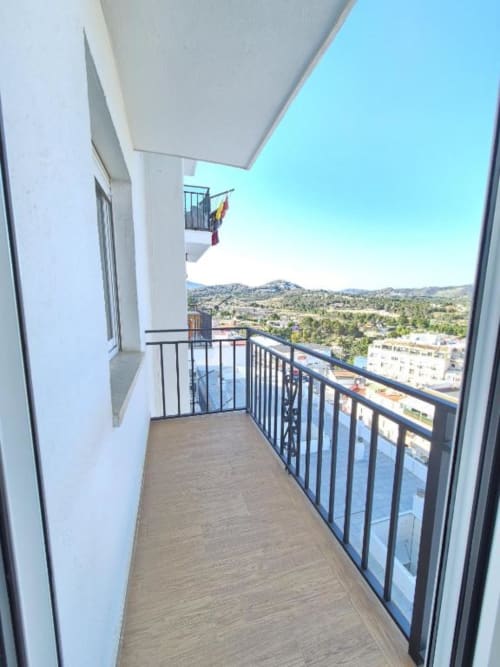 Balcón moderno de Aloha Calpe con vistas a montaña y ciudad, suelo de madera, barandilla metálica, cielo despejado, Calpe España