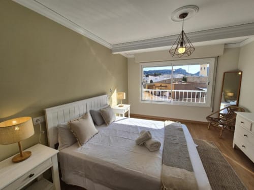 Habitación luminosa en Apartamento Aloha Calpe Old Town, Calpe, con vistas al mar y montaña desde balcón, cama blanca, suelo de madera