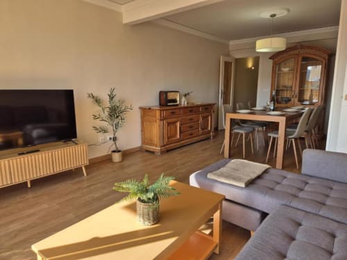 Salón moderno en apartamento del casco antiguo de Aloha Calpe con muebles de madera, sofá gris, comedor y vistas al mar
