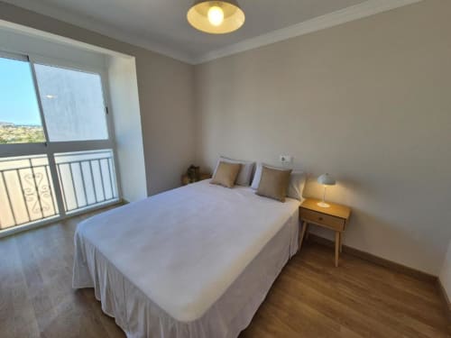 Dormitorio luminoso en apartamento del casco antiguo de Aloha Calpe con cama doble, balcón con vistas al mar, suelos de madera y comodidades modernas