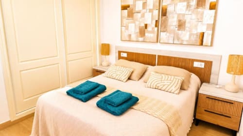 Dormitorio moderno del Aloha Calpe Dreams Apartment en Calpe con vistas al mar, cabecero de madera y toallas azules