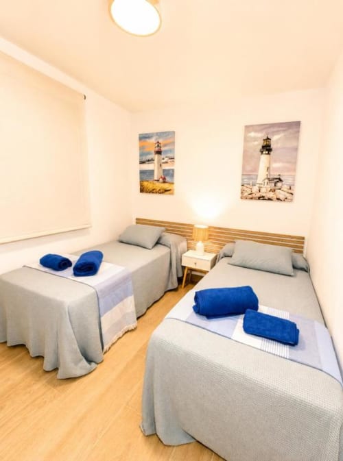 Dormitorio doble en apartamento Aloha Calpe con vistas al mar, cuadro con paisaje marino y toallas azules