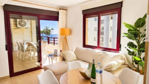 Luminoso apartamento con vista al mar en Aloha Calpe, salón moderno, sofá beige, comedor y balcón con vistas