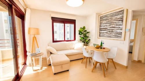 Luminosa sala de estar del Dreams Apartment en Aloha Calpe con sofá crema, comedor y vistas al mar desde el balcón