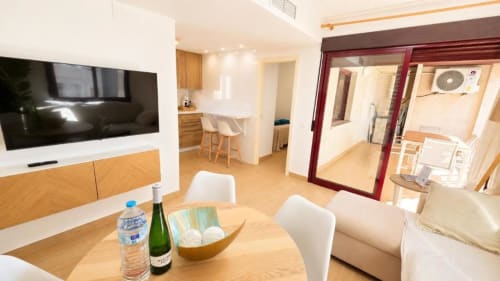 Amplia sala de estar en Dreams Apartment, Aloha Calpe, con comedor, cocina, TV y acceso a terraza con vistas al mar
