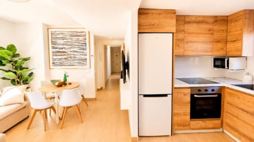 Cocina y sala de estar del apartamento Dreams en Aloha Calpe con muebles de madera, electrodomésticos modernos y mesa de comedor en Calpe,