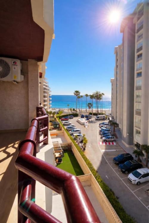 Vista de la terraza del apartamento Dreams con vistas a la playa de Calpe, palmeras y el mar Mediterráneo en el hotel Aloha Calpe