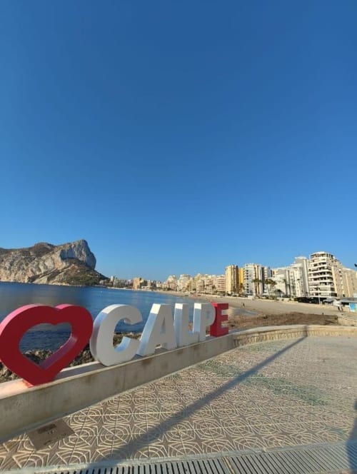 Cartel "I LOVE CALPE" con la roca Peñyal d'Ifach, playa y apartamentos frente al mar en Calpe, España