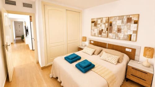 Dormitorio moderno en Dreams Apartment de Aloha Calpe con cama, mesillas de madera, armario y decoración costera en Calpe, España.