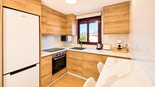 Cocina moderna en Dreams Apartment de Aloha Calpe con muebles de madera, electrodomésticos de acero inoxidable y vistas al mar en Calpe