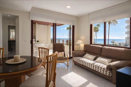 Apartamento Sea Palm en Aloha Calpe con vistas al mar, sala con sofá marrón, comedor y balcón con vistas a palmeras