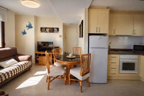 Sala de estar del Apartamento Sea Palm en Calpe con cocina, mesa de comedor, sofá, TV y vistas al mar