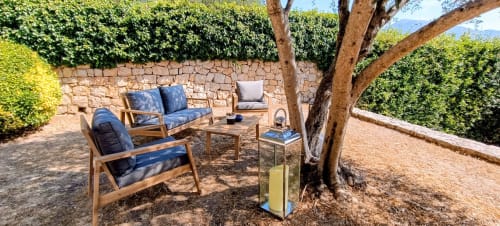 Schaduwrijk zitgedeelte met houten meubels en blauwe kussens in de privétuin van Loup Castel Boutique Hotel