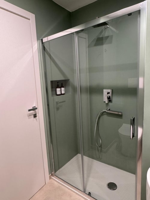 Moderna cabina doccia in vetro con pavimento in piastrelle bianche e pareti in piastrelle verdi nel bagno dell'appartamento Maison ì Room, Reggio