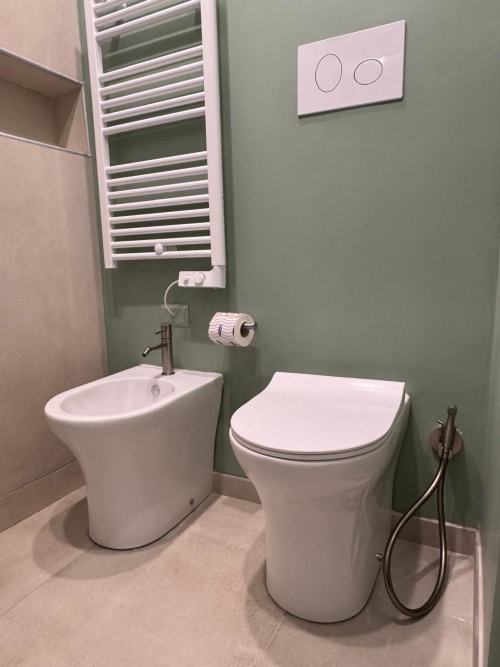 Bagno moderno nell'appartamento di Reggio Calabria con bidet bianco, wc, scaldasalviette e pareti verdi