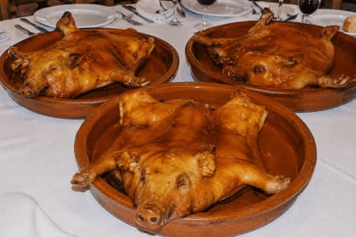 Lechoncillos asados servidos en bandejas de madera en Senda del Duratón Apartments, restaurante rural español en Sebúlcor.
