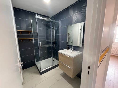 Salle de bains moderne chez Mattbnb Metz avec douche carrelée noire, meuble-lavabo en bois et miroir