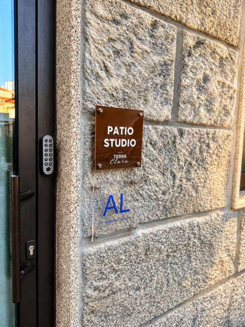 Entrada do Terra Clara Studio em Esposende com placa Patio Studio castanha em parede de pedra e teclado digital
