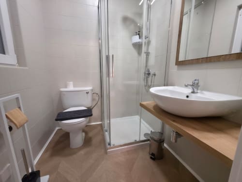 Bagno moderno con piastrelle bianche, lavabo rotondo, wc e doccia con box in vetro presso l'appartamento Calm Holiday Homes a San