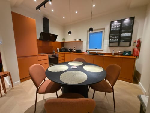 Cucina moderna arancione con tavolo da pranzo tondo nero e sedie maroni nell'appartamento Calm Holiday Homes, San Julian's Malta