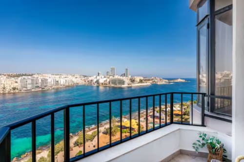 Vista dal balcone della costa di Sliema con il mare Mediterraneo turchese, spiaggia sabbiosa e skyline dalla Calm Holiday Homes