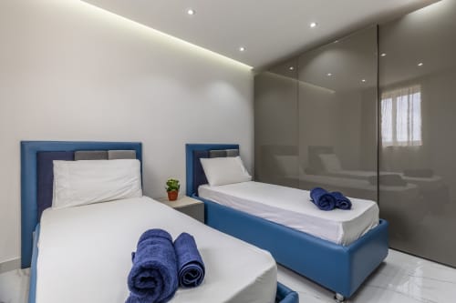 Camera da letto moderna con due letti blu presso il lussuoso penthouse di Calm Holiday Homes a Ta-Xbiex, Marsa con vista sulla città