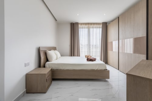 Camera da letto di lusso nella penthouse di Calm Holiday Homes a Marsa con arredamenti moderni in legno, pavimentazione in marmo, vista sulla città e