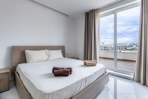 Lussuosa camera da letto in penthouse a Marsa con vista sulla città, letto bianco, accesso alla terrazza e arredamento moderno