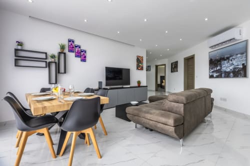 Lussuosa zona living del pentahouse a Ta-Xbiex con tavolo da pranzo, divano grigio, TV e vista sulla città presso Calm Holiday Homes
