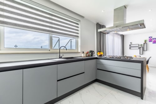 Cucina di lusso moderna nel penthouses di Ta-Xbiex con armadi grigi, piani neri, piano cottura a gas e vista sulla città di Marsa