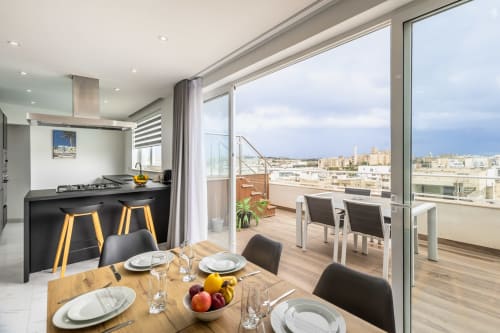 Esclusiva zona pranzo nel penthouse di Marsa con vista sulla città, cucina moderna e terrazza con panorama sullo skyline di Ta-Xbiex