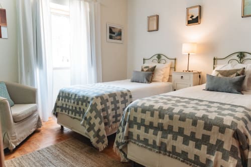 Bright twin bedroom in Cascais Garden House with patterned blankets, garden view, modern amenities and natural light