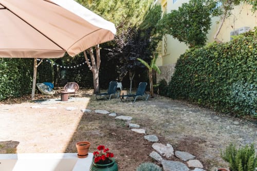 Cascais Garden House outdoor patio with loungers, umbrella, and stone pathways surrounded by lush greenery