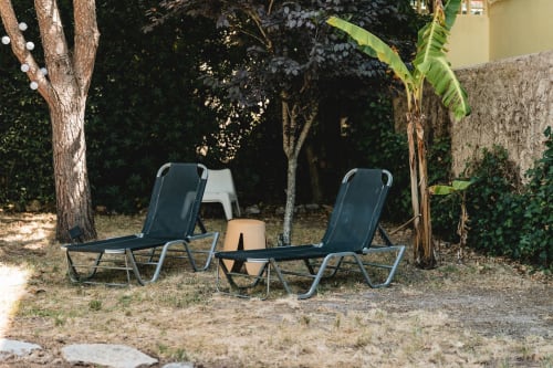 Shaded garden lounge area at Arestas e Planetas in Cascais with two reclining chairs and small table