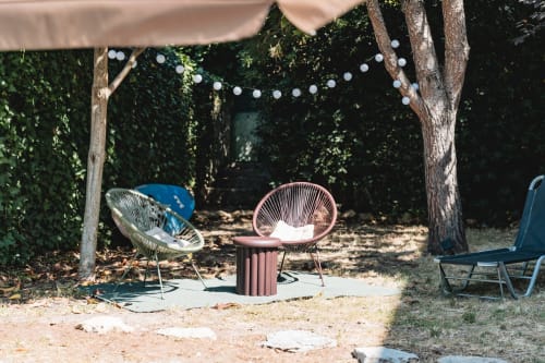 Cascais garden patio with modern pink and white chairs, string lights, and lush ivy-covered walls at Arestas e Planetas