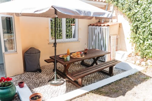 Cascais Garden House terrace with wooden dining table, parasol, and garden views in Portugal