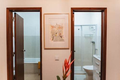 Cascais Garden House hallway with wooden doors, red flower, and artwork on beige wall