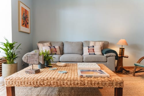 Bright living room at Cascais Garden House with gray sofa, woven coffee table, potted plants, and warm lighting