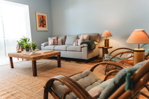 Bright living room at Arestas e Planetas in Cascais with beige sofa, wicker coffee table, rattan chairs, and warm lamps