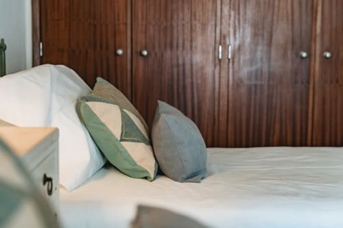 Modern bedroom at Arestas e Planetas in Cascais with decorative pillows on bed and wooden wardrobe