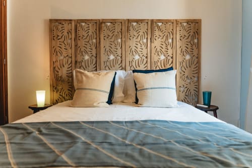 Modern bedroom in Cascais Garden House with carved wooden headboard, cream bedding, and teal accents