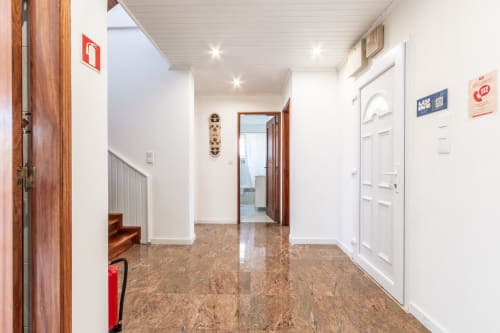 Entrada moderna do hall da villa Arestas e Planetas em Amora, Portugal, com piso de cortiça e portas brancas