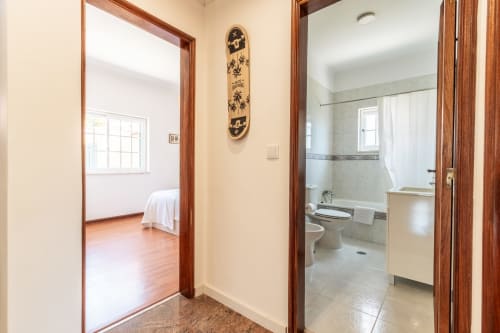 Corredor da villa Arestas e Planetas com portas de quarto e casa de banho com marcos de madeira em Amora, Portugal