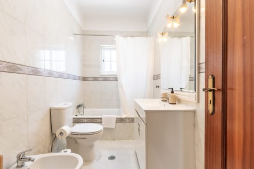 Banheiro moderno da villa Arestas e Planetas, Amora, com azulejos brancos, pia, vaso sanitário e box de chuveiro