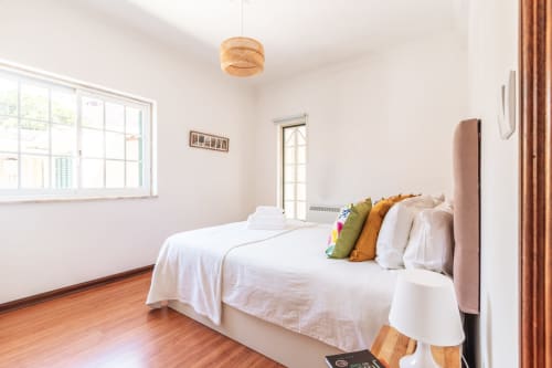 Quarto luminoso na villa Arestas e Planetas perto de Caparica com pisos de madeira, almofadas coloridas e luminária de vime