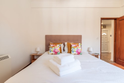 Quarto luminoso na villa Arestas e Planetas perto de Caparica com cama queen, almofadas floridas e banheiro ensuite