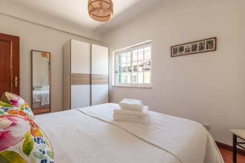 Quarto luminoso com cama queen, lençol branco impecável, almofada colorida, guarda-roupa espelhado e vista para o jardim em Arestas e Planetas