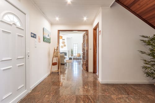Corredor de villa moderna em Amora com piso de cortiça, paredes brancas, portas de madeira e iluminação contemporânea levando à sala de estar