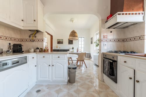Cozinha moderna com armários brancos, eletrodomésticos em aço inoxidável e layout em plano aberto na villa Amora perto de Caparica